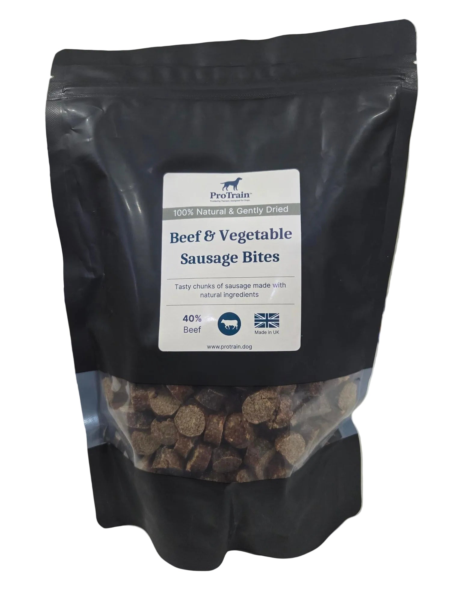 A black stand-up pouch of ProMax Beef & Vegetable Sausage Bites dog food, with a clear window showing the brown kibble inside, photographed on a light surface.